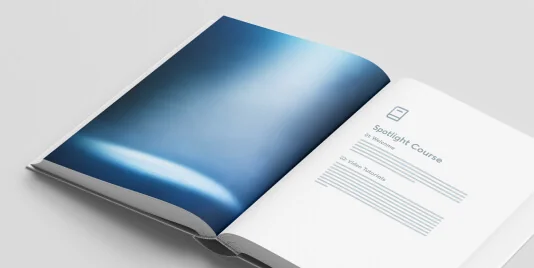 Open booklet lies open on a white surface, displaying a blue abstract photo opposite a minimal title page (object-action-context).