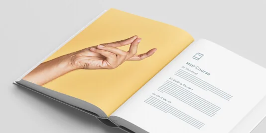Open booklet: a hand makes a meditative mudra on a yellow left page while the right white page lists course contents in a clean layout.