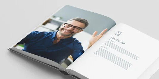 Open book lying on a gray surface: left page shows a smiling man with glasses waving; right page displays a minimal course layout and placeholder...