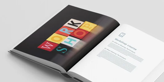 Open booklet lies on a white surface, showing colorful letter blocks that spell WORKSHOP on the left; right page titled Workshop course with...