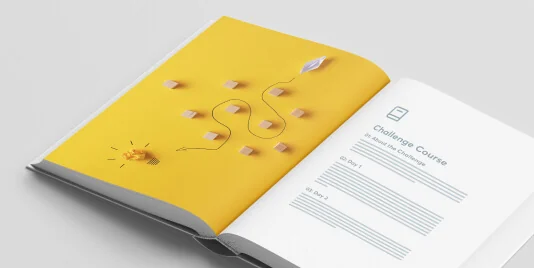 An open booklet lies on a white surface; left yellow page shows wooden blocks connected by a winding string, a paper plane and crumpled idea-ball;...