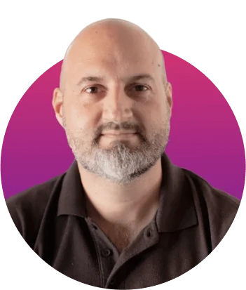 Bearded bald man looks directly at camera with neutral expression; wearing a dark polo shirt; portrait cropped inside a circular pink-to-purple...