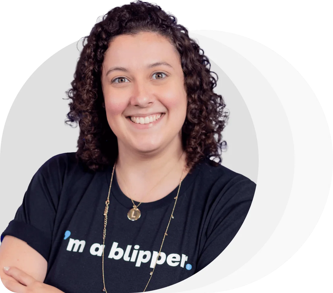 Person with curly hair smiling at the camera, arms crossed, wearing a black T-shirt reading "i'm a blipper.