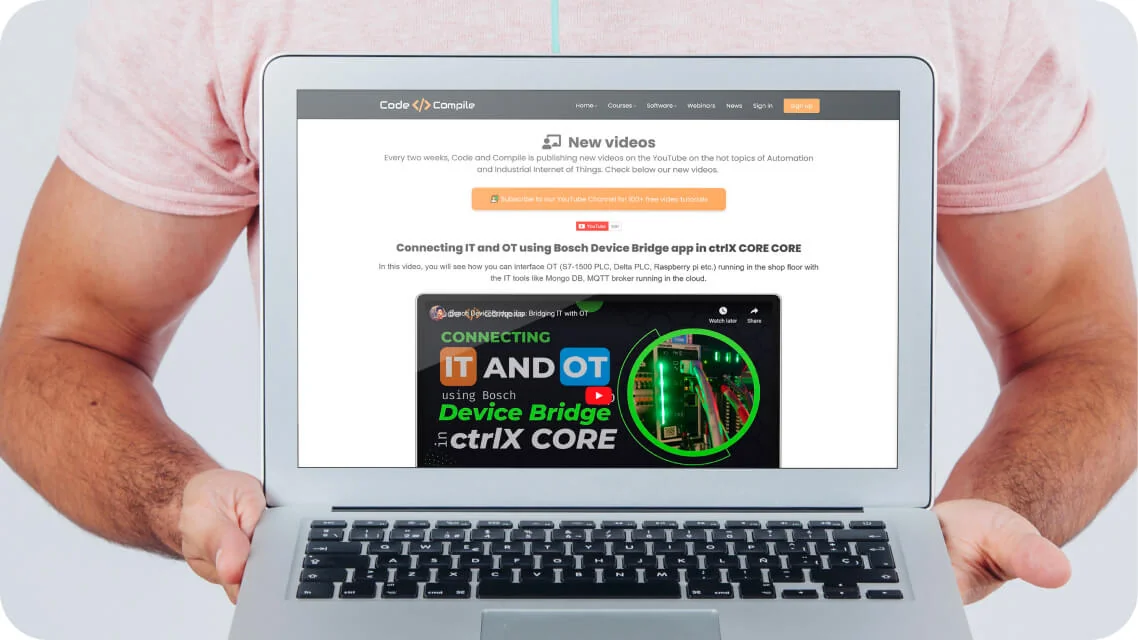 A laptop is held by a person, displaying a webpage about new videos on connecting IT and OT, featuring a descriptive paragraph, an orange subscribe...