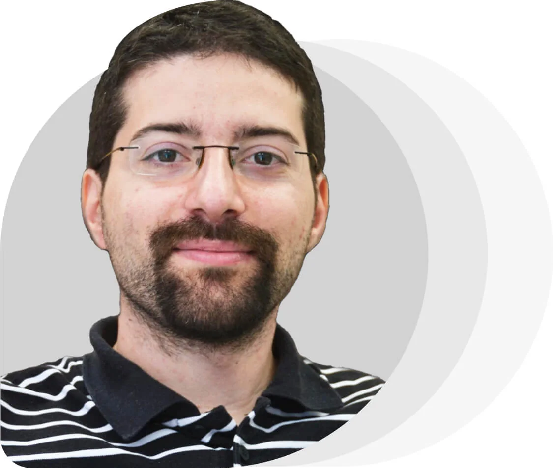 Adult man with glasses and short dark hair, slight smile, facing the camera; wearing a black-and-white striped polo; centered against layered...