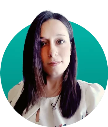 A woman gazes directly at the camera with a neutral expression; wearing a white patterned blouse and straight dark shoulder-length hair; centered...