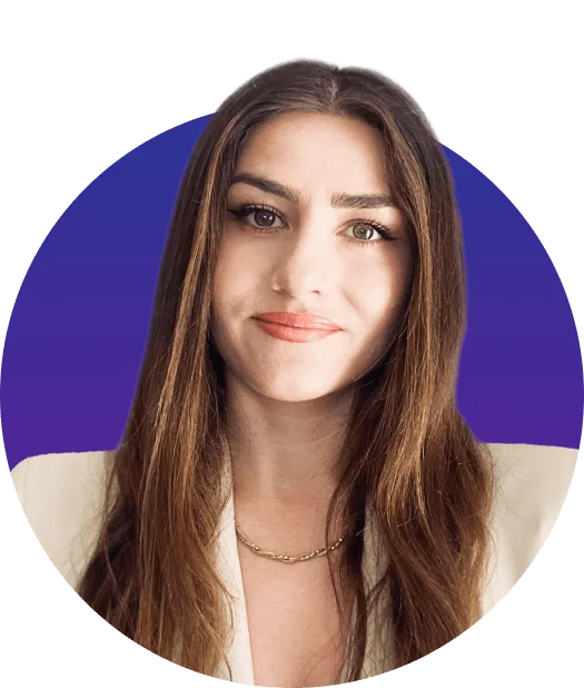 A brown-haired woman wearing a white blazer and gold chain necklace looks directly at the camera with a soft smile, framed by a circular...