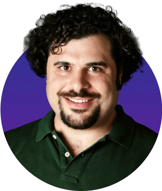Smiling man with dark curly hair and goatee, wearing a green polo, facing the camera against a circular purple backdrop.