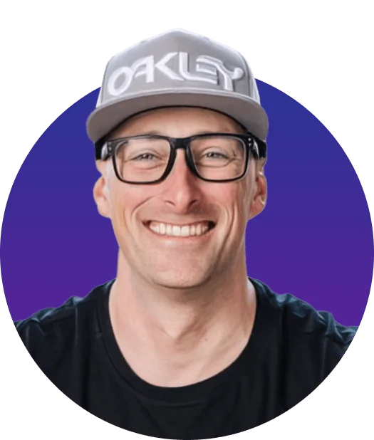 Smiling man wearing a gray cap labeled "OAKLEY" and thick black glasses smiles directly at the camera, shoulders visible, against a circular...