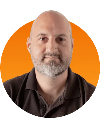 Bald, bearded man looking directly at the camera with a neutral expression, wearing a dark polo; circular portrait crop set against a warm orange...