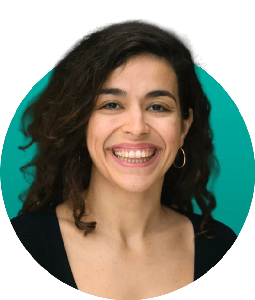 Smiling woman with curly dark hair and hoop earrings, showing teeth; wearing a black top.