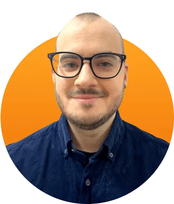 Person with short hair and glasses smiles subtly, facing the camera; wearing a dark blue button-up shirt; centered against a bright orange circular...