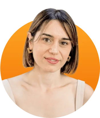 Woman with short brown hair gazes at camera, faint smile, wearing a sleeveless top and geometric earrings against a bright orange circular background.