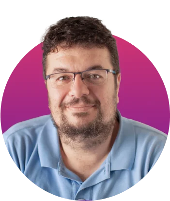 Adult man with short curly dark hair, beard, and glasses wearing a light-blue polo looks at the camera with a gentle smile against a circular...