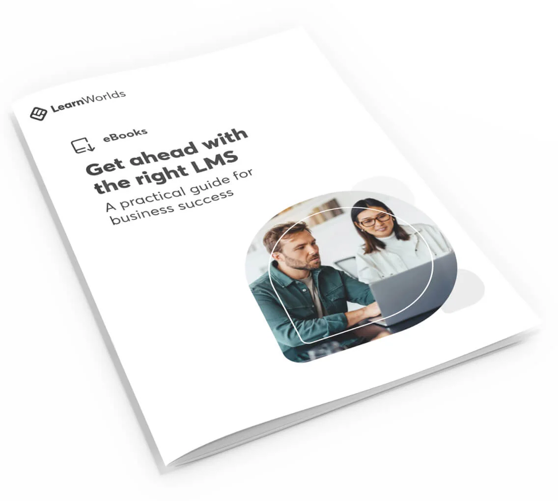 A softcover booklet lies angled on a white surface, showing two colleagues at a laptop and bold cover text promoting a practical LMS guide.