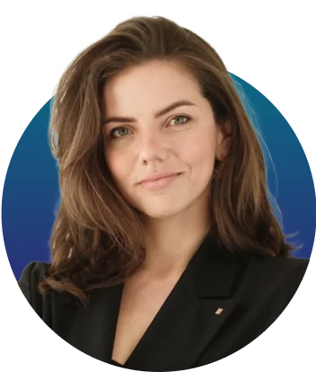 Adult woman with shoulder-length brown hair, slight smile and direct gaze, wearing a black blazer with small lapel pin; posed front-facing against a...