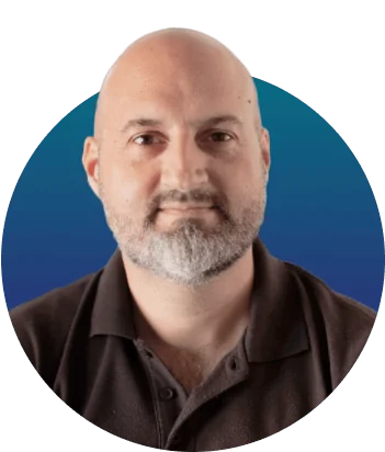 Adult bald man with salt-and-pepper beard looks directly at camera with a neutral expression; cropped portrait on a circular blue gradient...