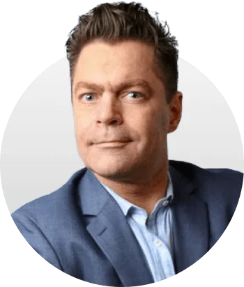 Male head-and-shoulders portrait, wearing a blue suit and light-blue shirt, looking directly at the camera with a neutral expression, short brown...